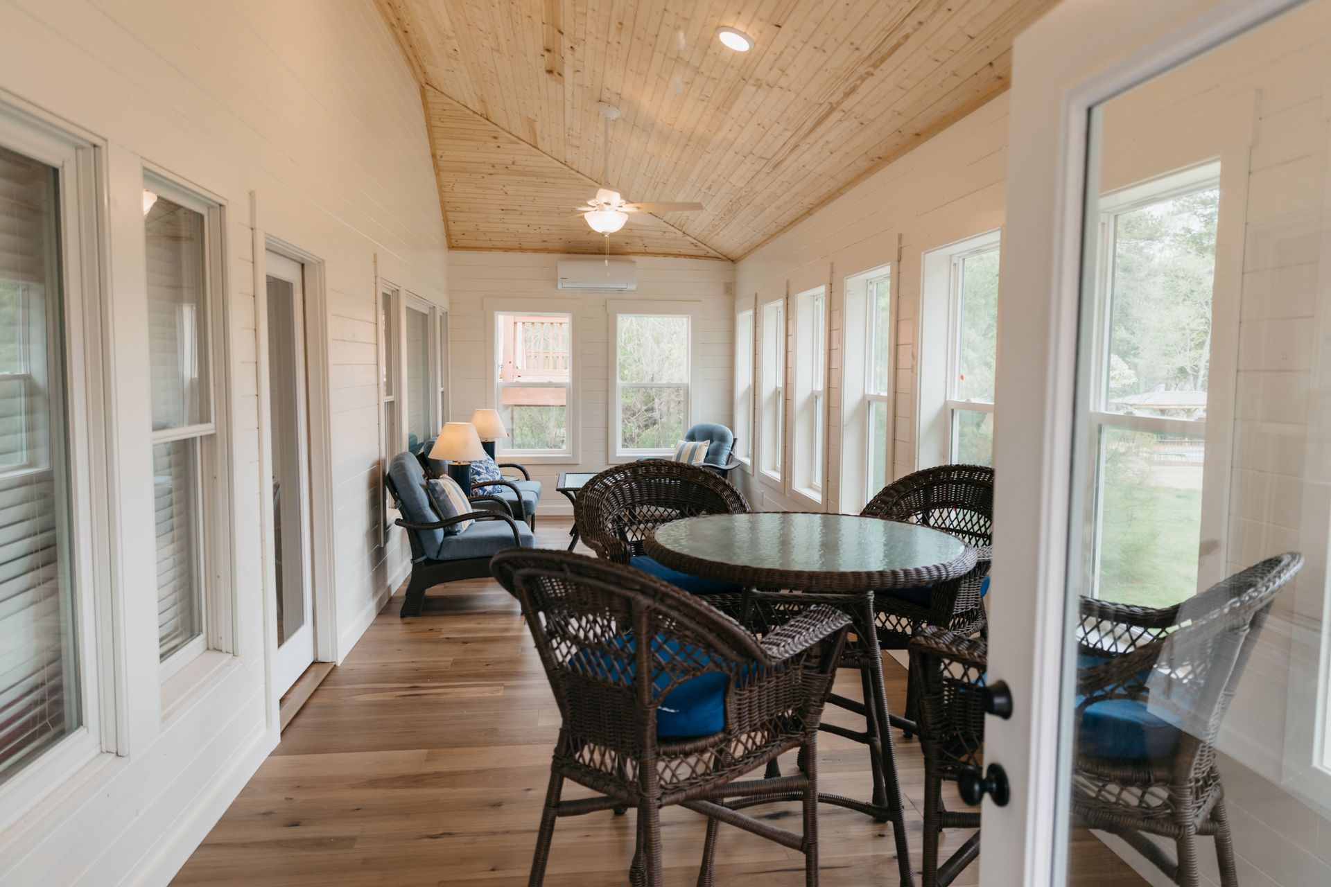 A long porch with a table and chairs and a lot of windows.