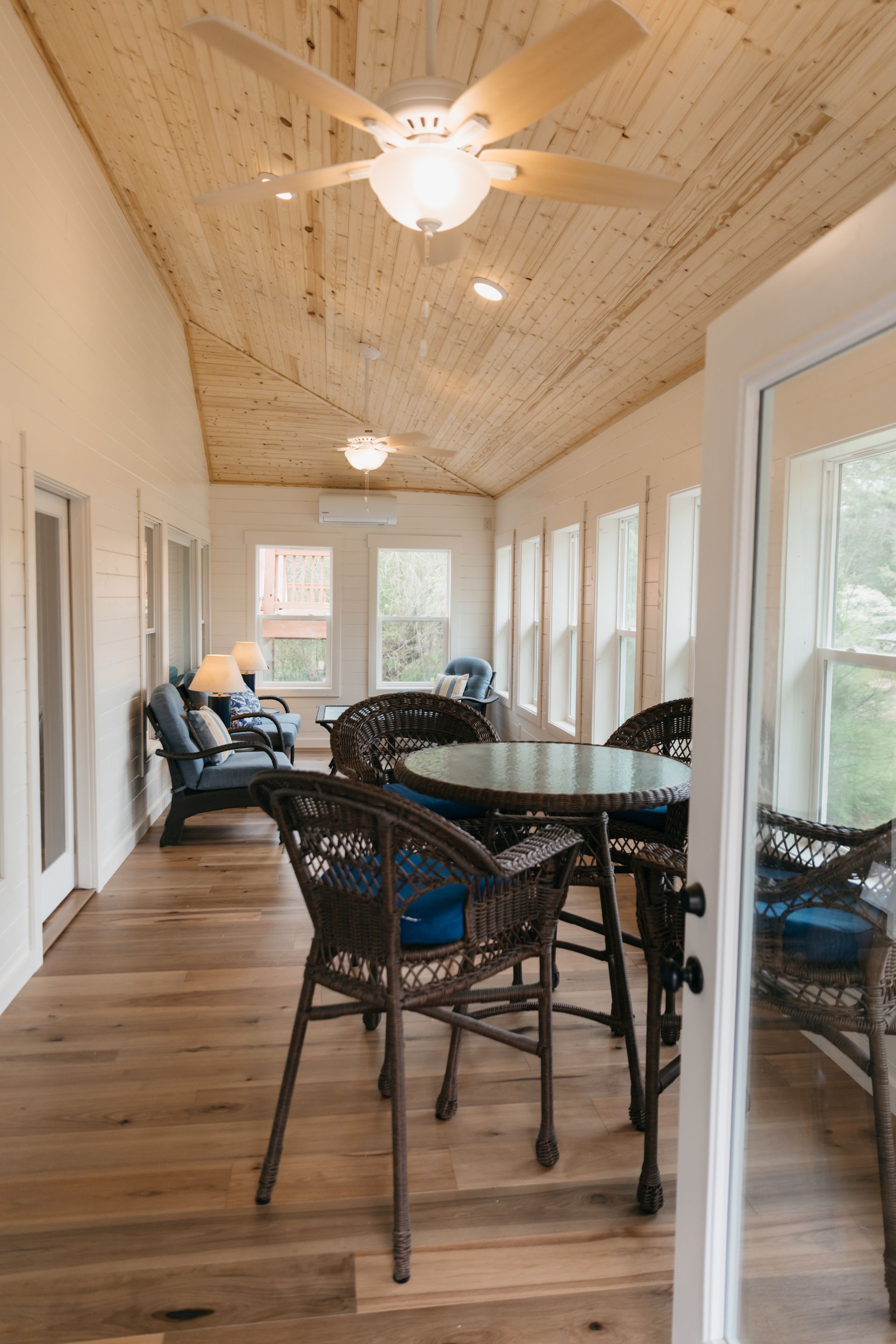 A sun room with a table and chairs and a ceiling fan.