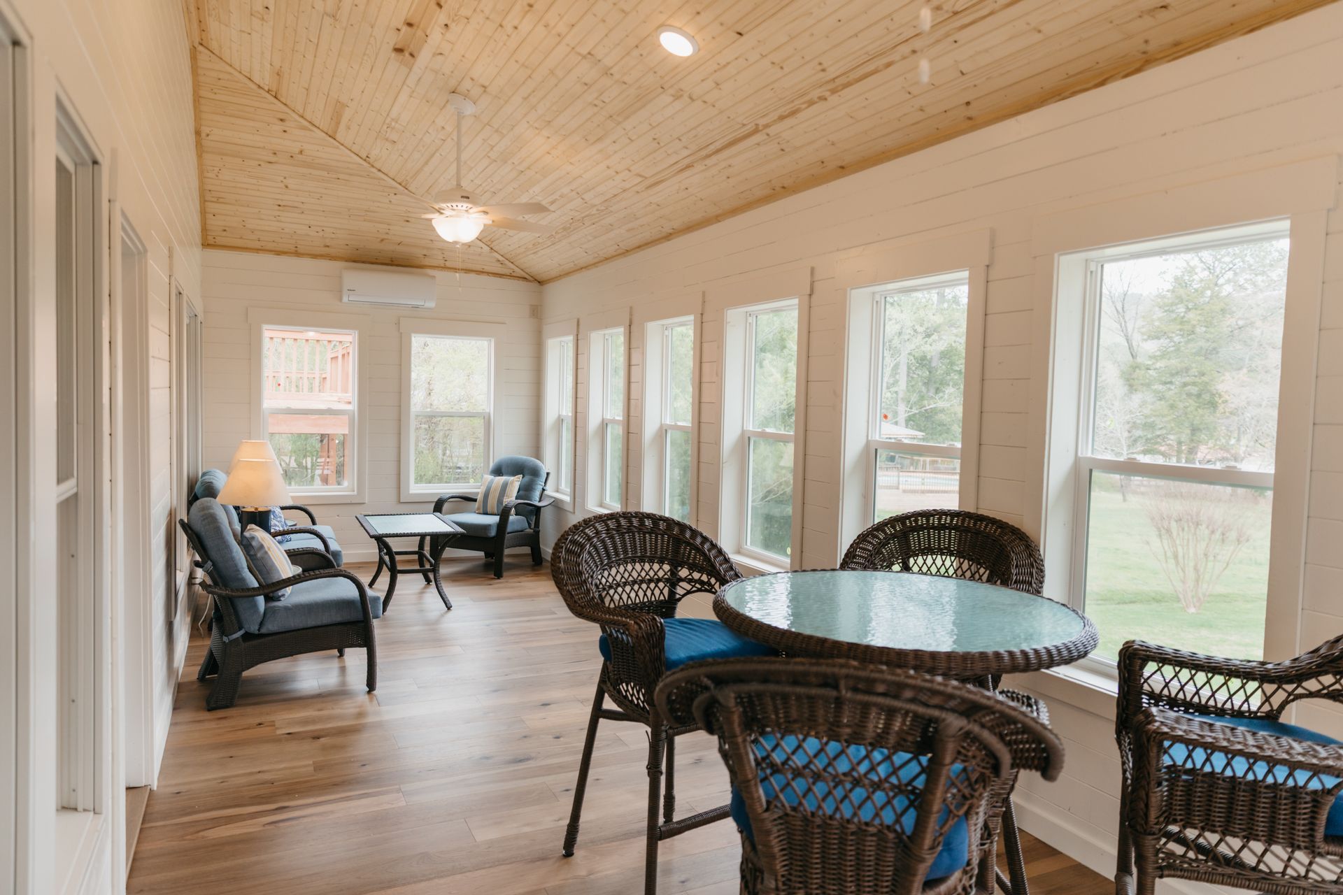 A living room with a table and chairs and a lot of windows.