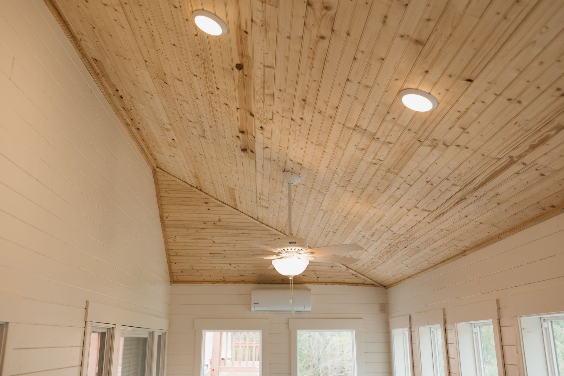 A room with a wooden ceiling and a ceiling fan.