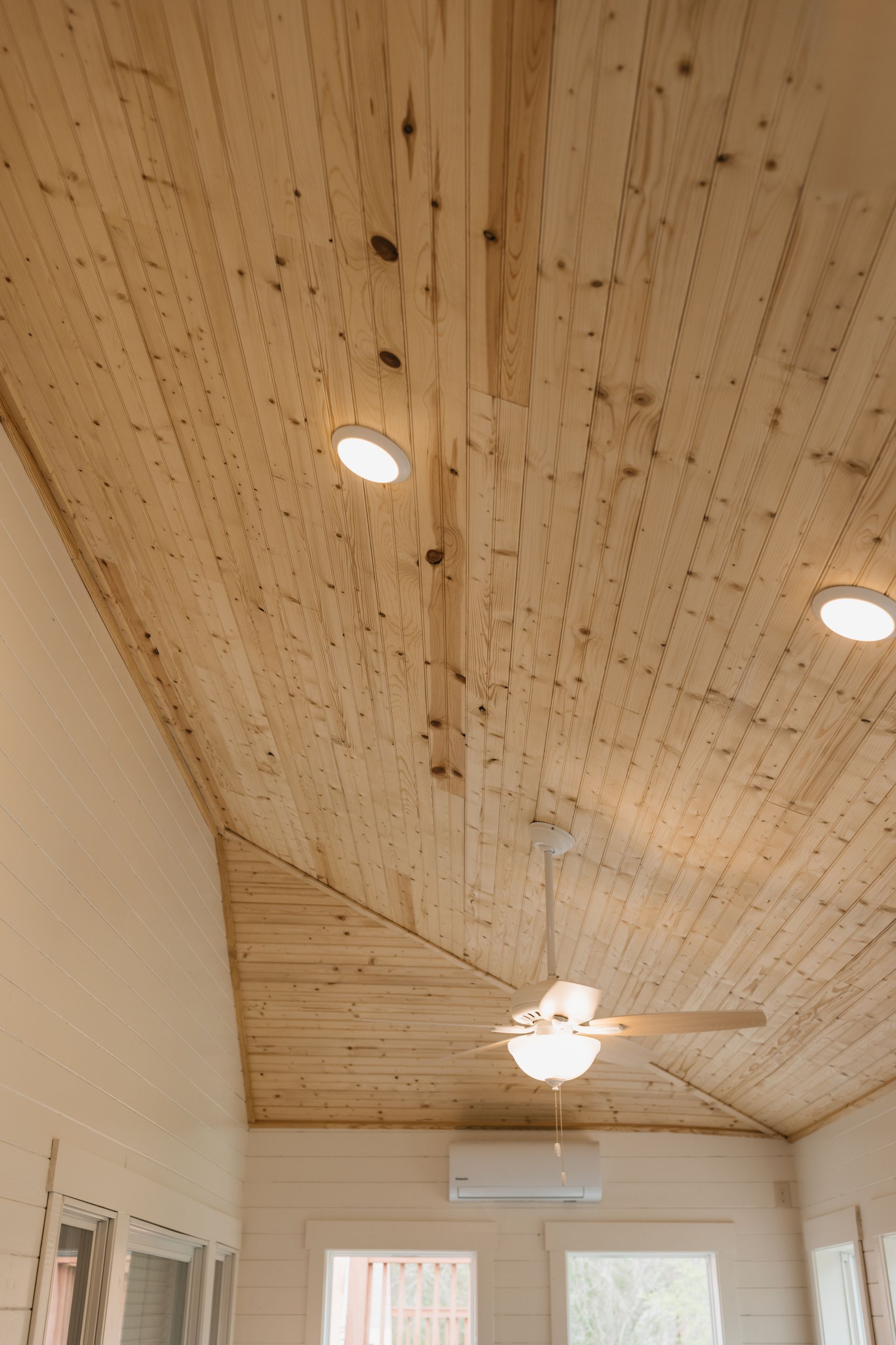 A room with a wooden ceiling and a ceiling fan.