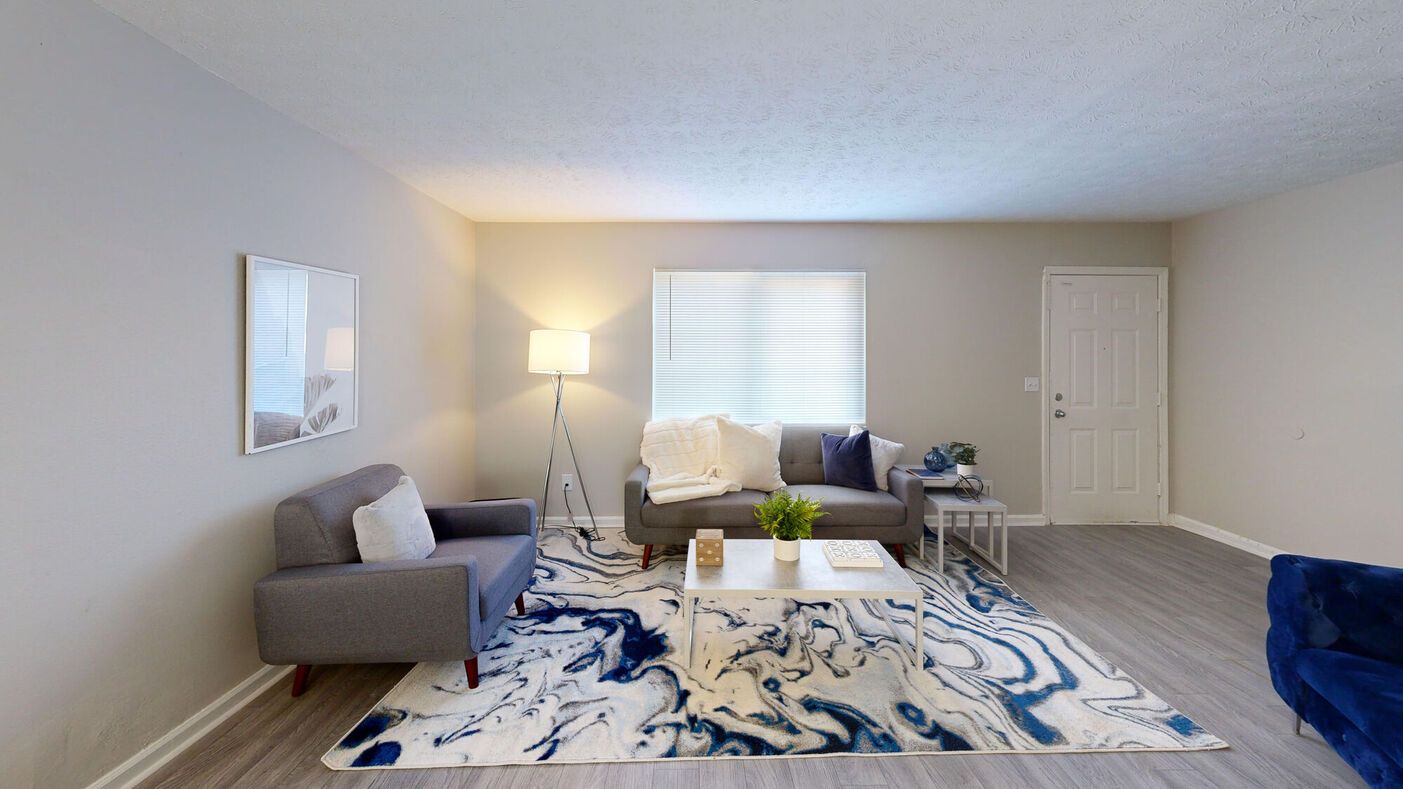 Living room with gray couches, a blue rug, and white walls.