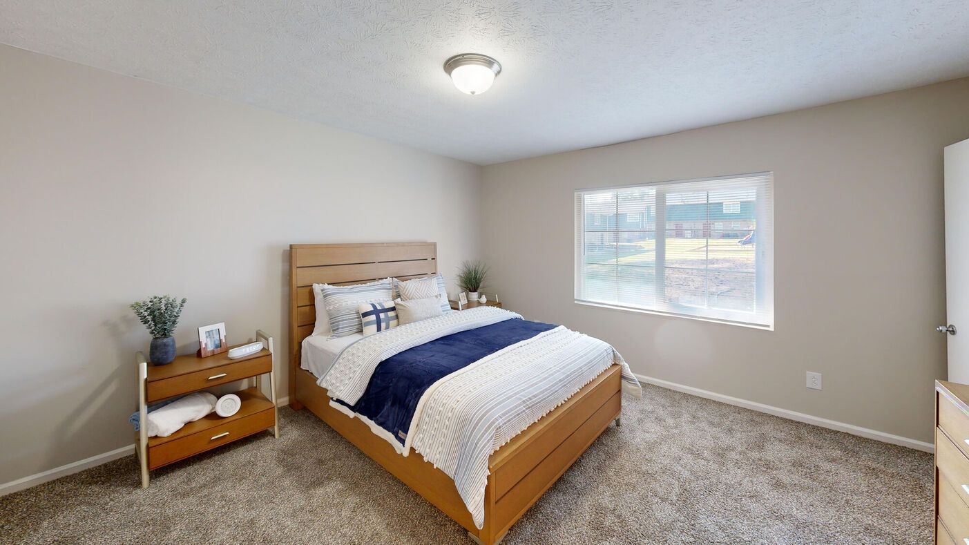 Bedroom with wooden bed and furniture, carpet flooring, and window.
