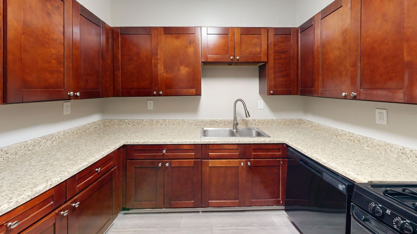 Dark wood kitchen cabinets and countertops with a stainless steel sink and black stove.