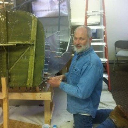 A man in a blue shirt is kneeling down in front of a ladder