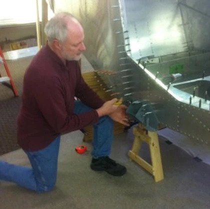 A man is kneeling down in front of a piece of metal