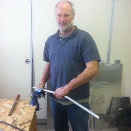 A man in a blue shirt is holding a piece of metal