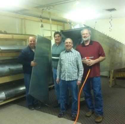 A group of men standing in a room holding a piece of metal