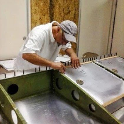 A man in a hat is working on a piece of metal