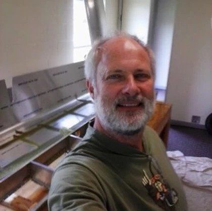 A man with a beard is taking a selfie in a kitchen.