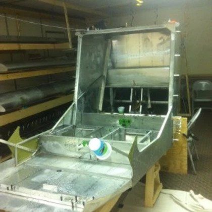 A metal boat is sitting on a wooden table in a room