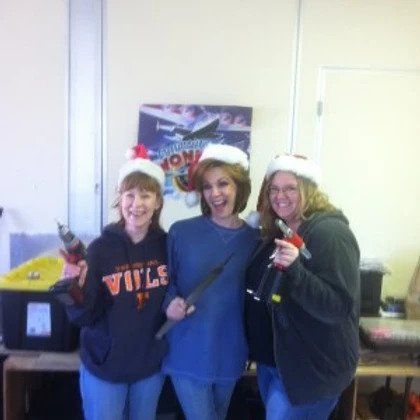 Three women wearing santa hats are posing for a picture