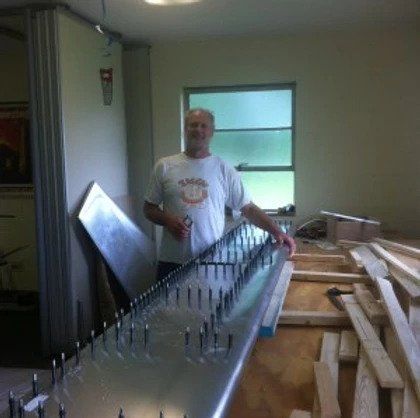 A man in a white shirt is standing next to a table with nails on it