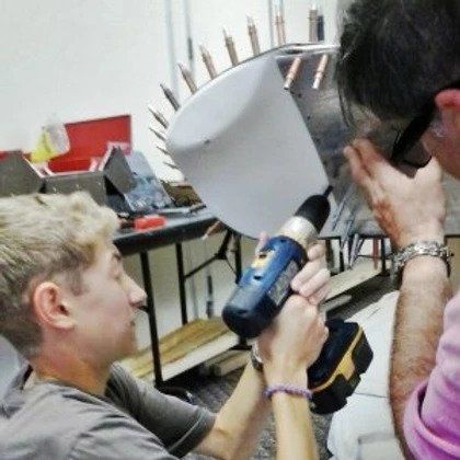 A man is holding a drill while another man looks on