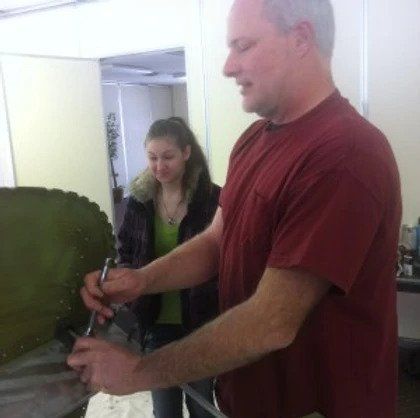 A man in a red shirt is cutting a piece of cake