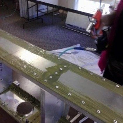 A person is working on a piece of metal on the floor