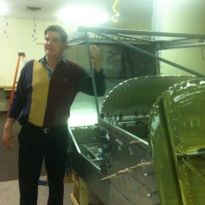 A man is standing in front of a boat that is being built