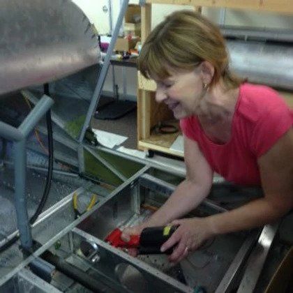 A woman in a pink shirt is working on a machine