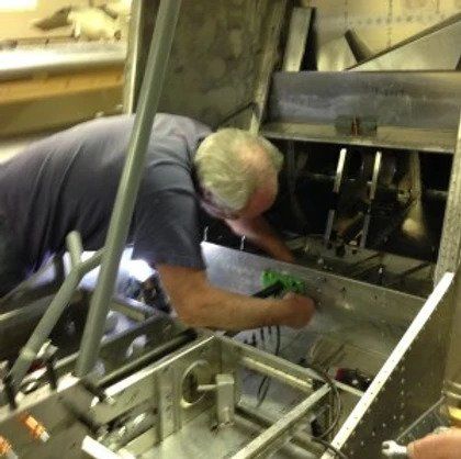 A man in a blue shirt is working on a piece of metal
