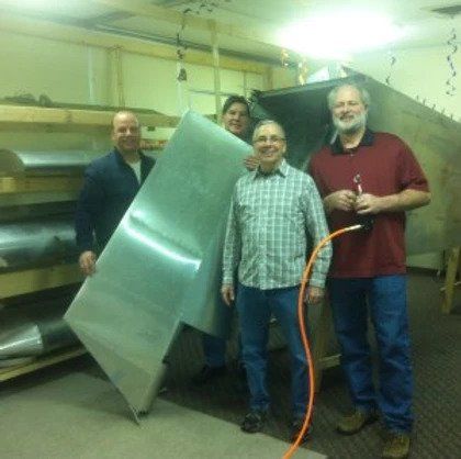 A group of men standing next to each other holding a large piece of metal