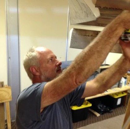 A man with a beard is working on a piece of wood