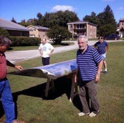 A man in a striped shirt is holding a large piece of metal