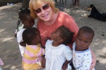 A woman is holding a group of children in her arms.
