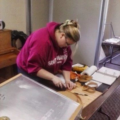 A woman wearing a south haven sweatshirt is working on a project