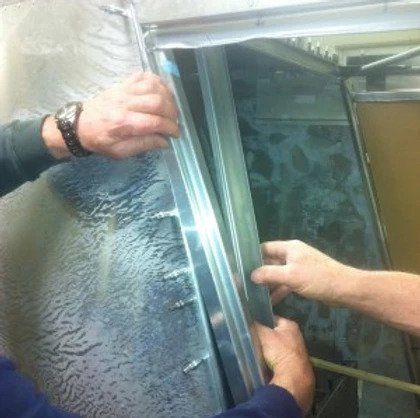 A couple of people are working on a piece of metal.