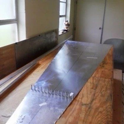 A piece of metal is sitting on top of a wooden table.
