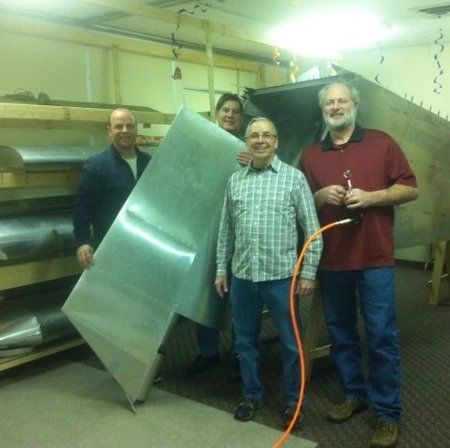 A group of men standing next to each other holding a large piece of metal