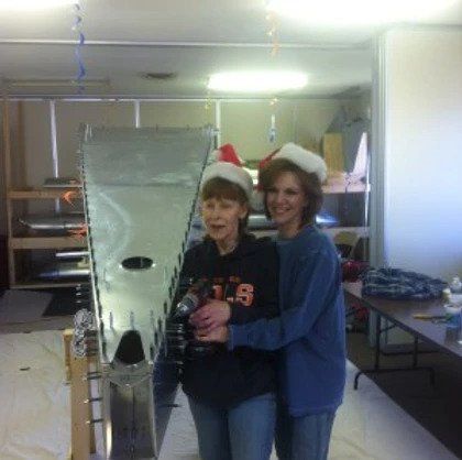 Two women wearing santa hats are posing for a picture