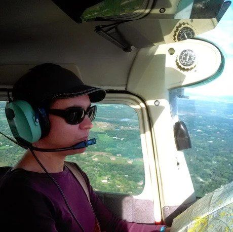 A man wearing headphones and sunglasses is flying a plane