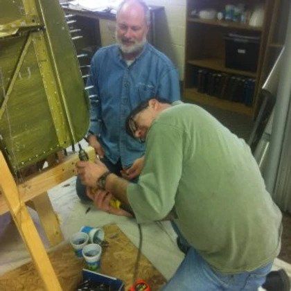 Two men are working on a piece of equipment on the floor