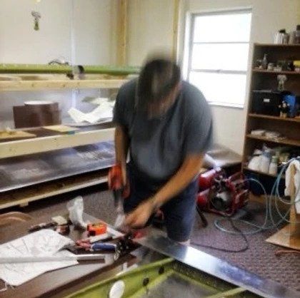 A man is working on a piece of metal in a room