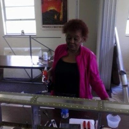 A woman in a pink jacket is standing in front of a table