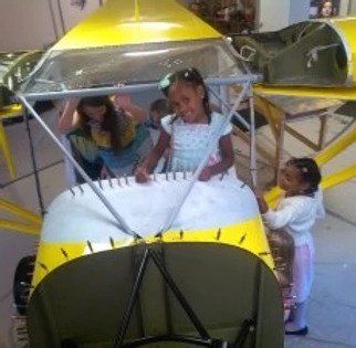 A group of children are playing in a toy airplane.