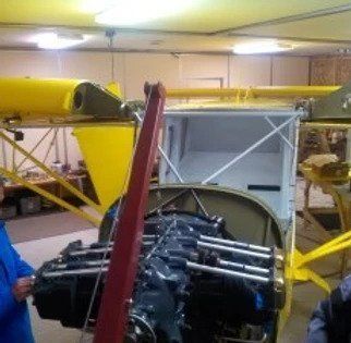A man is working on a small airplane engine in a garage.