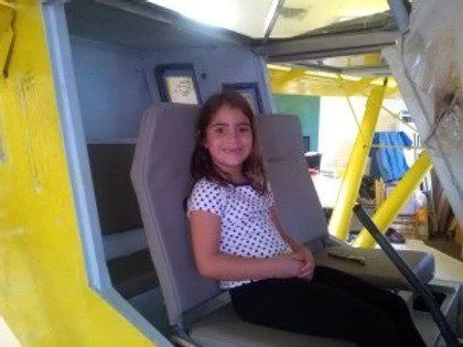 A little girl is sitting in the back seat of an airplane