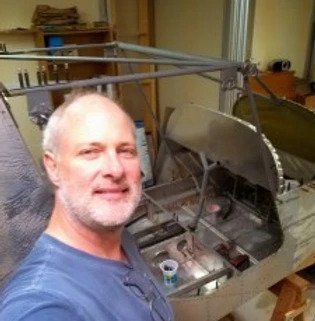 A man with a beard is taking a selfie in front of a metal structure.