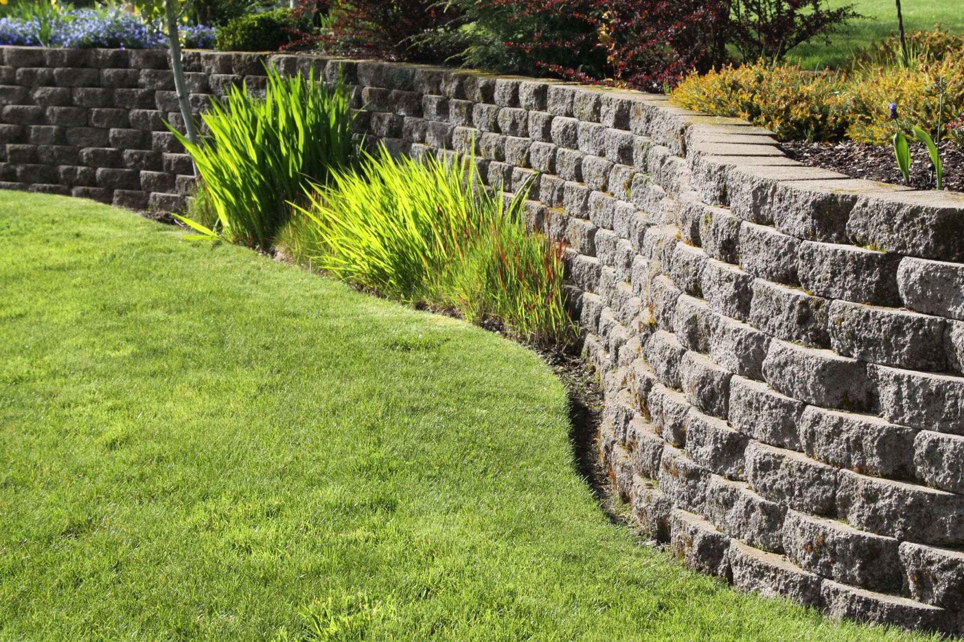 Sturdy retaining wall made of concrete blocks, providing structural support and preventing soil erosion in a landscaped garden.