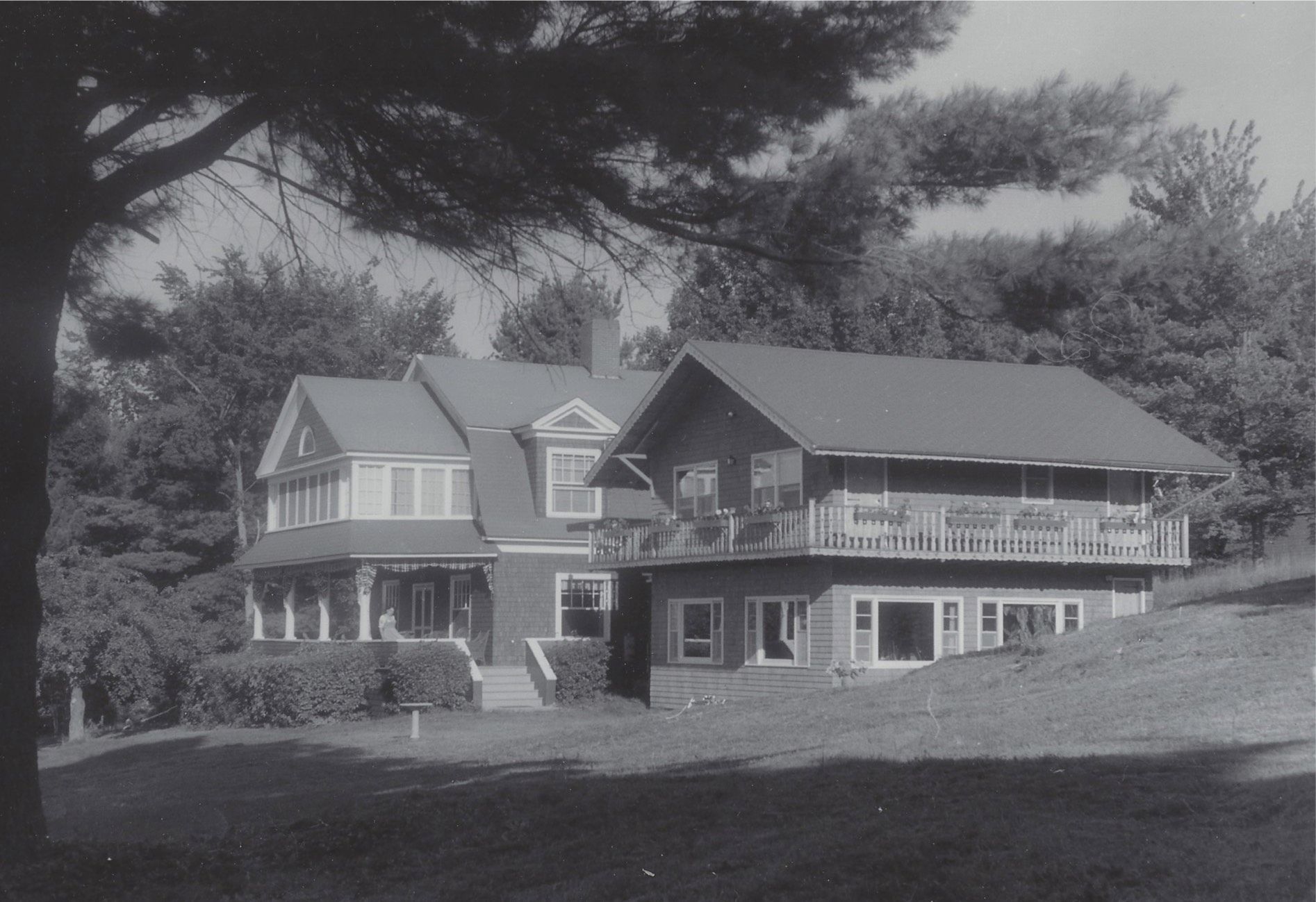 A black and white photo of a large house surrounded by trees