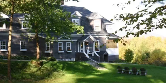 A large house with a lot of windows is surrounded by trees and grass.