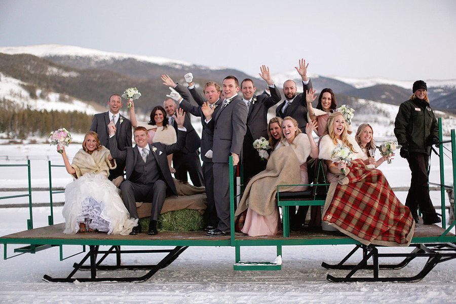 A wedding party is posing for a picture on a sled in the snow.