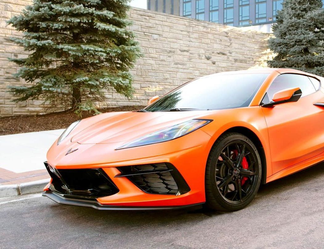an orange sports car is parked on the side of the road .