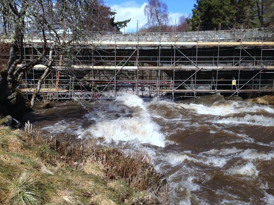 A bridge is being built over a river surrounded by scaffolding.