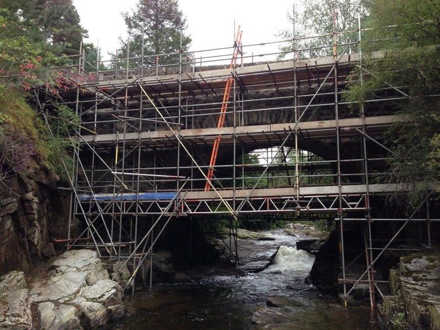 A bridge is being built over a river with scaffolding around it
