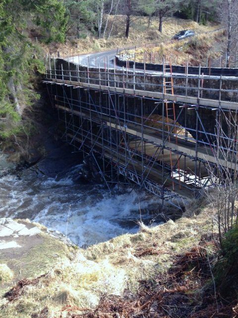 A bridge is being built over a river with scaffolding around it.