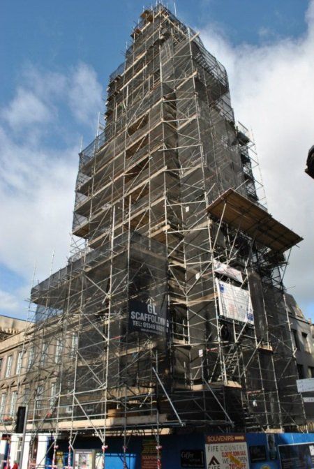 A tall building with scaffolding around it and a sign that says ' scaffolding ' on it