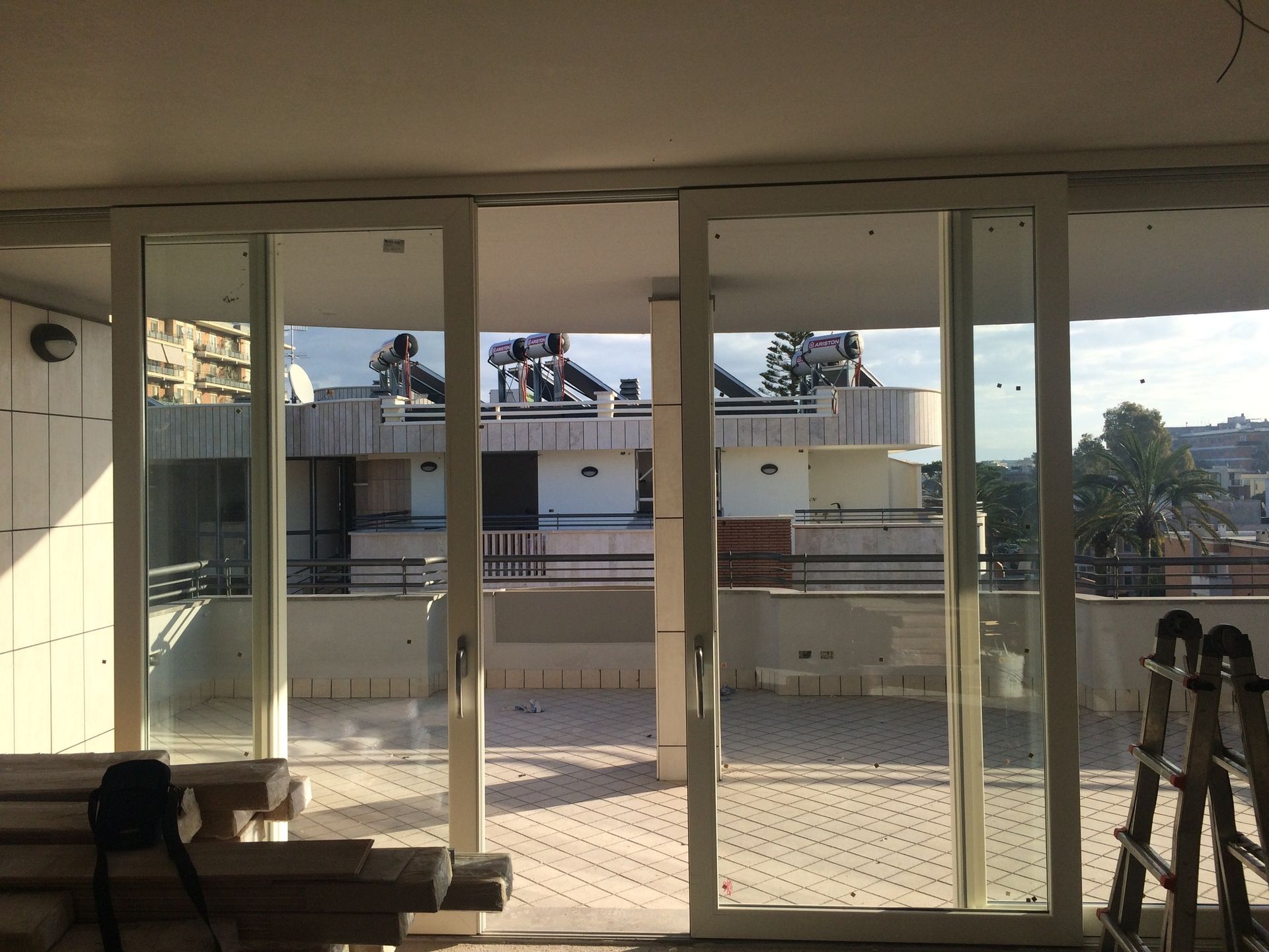 Le porte scorrevoli in vetro si aprono su un balcone soleggiato con vista sui tetti e sulla città Mz Sistemi Latina